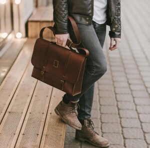 Man carrying brown leather satchel bag with buckle straps – Leather and Kid
