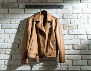 Tan leather biker jacket hanging against a brick wall – Leather and Kid