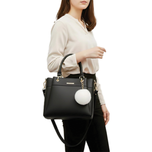 Leather and Kids black leather handbag with white pom-pom charm worn on model's shoulde