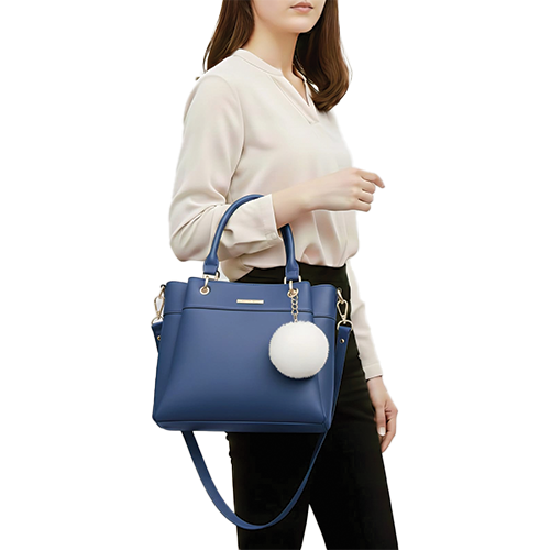 Leather and Kids navy blue leather handbag with white pom-pom charm worn on model's shoulder