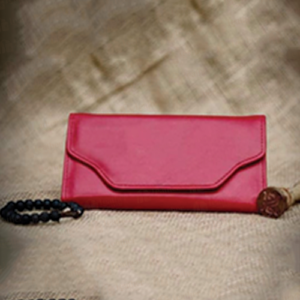 Magenta Leather Envelope Wallet shown as a magenta wallet with beaded wristlet strap featuring a braided cord and round bead accent.